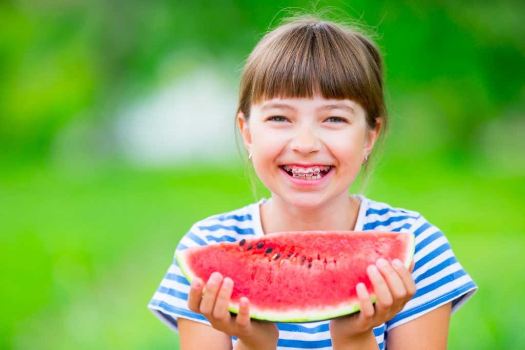 girl with braces eating a watermelon
